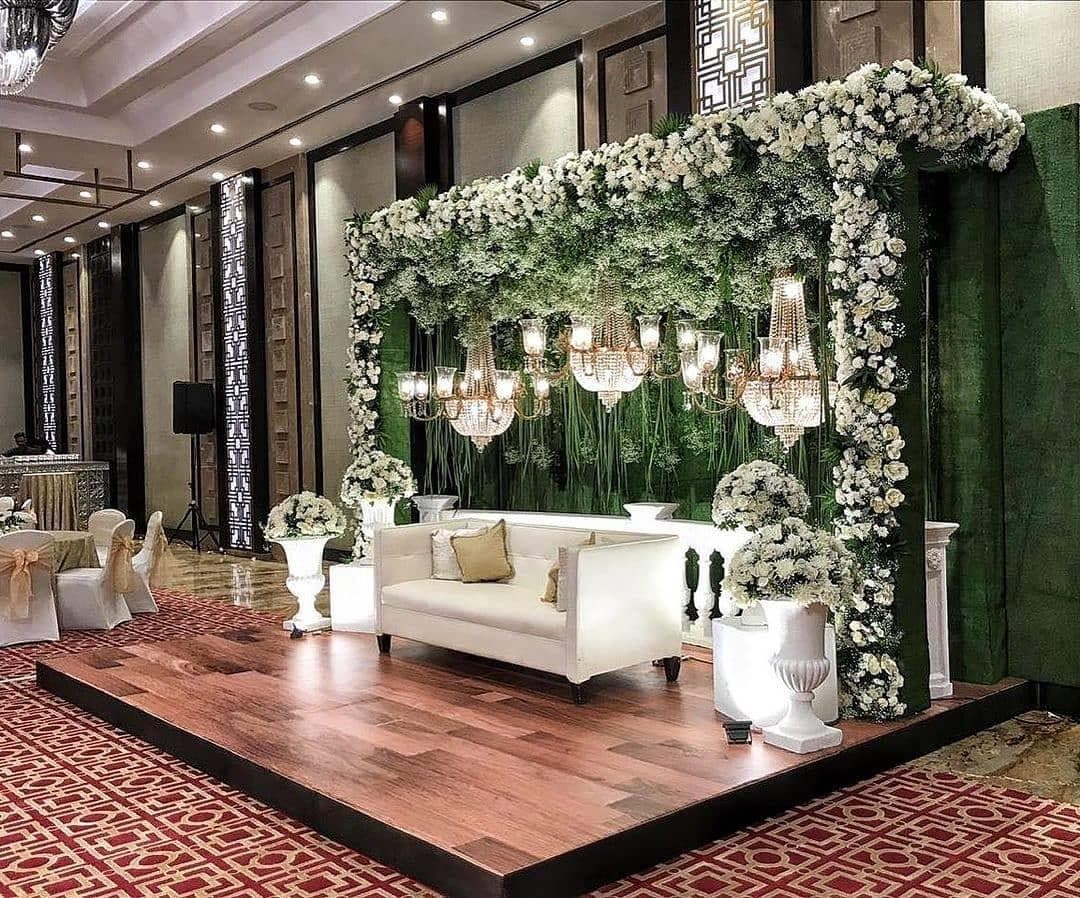 White floral wall backdrop with crystal chandeliers and lounge seating